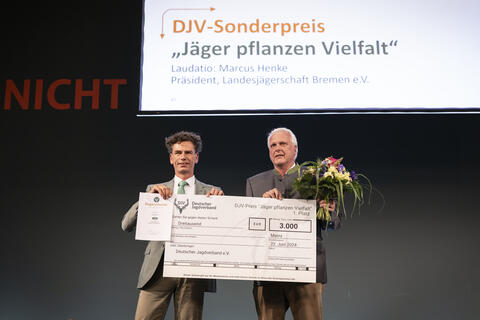 Jurymitglied und Juror Marcus Henke (l.) übergibt den Scheck für den ersten Platz des DJV-Sonderpreises "Jäger pflanzen Vielfalt" an die Jägerschaft Aurich